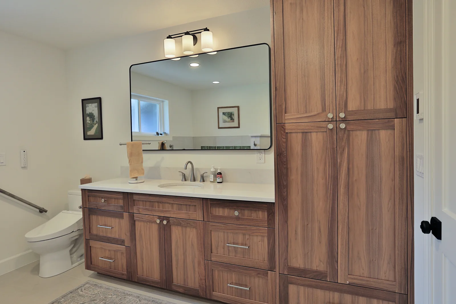 Custom walnut bathroom vanity and linen tower with quartz counter