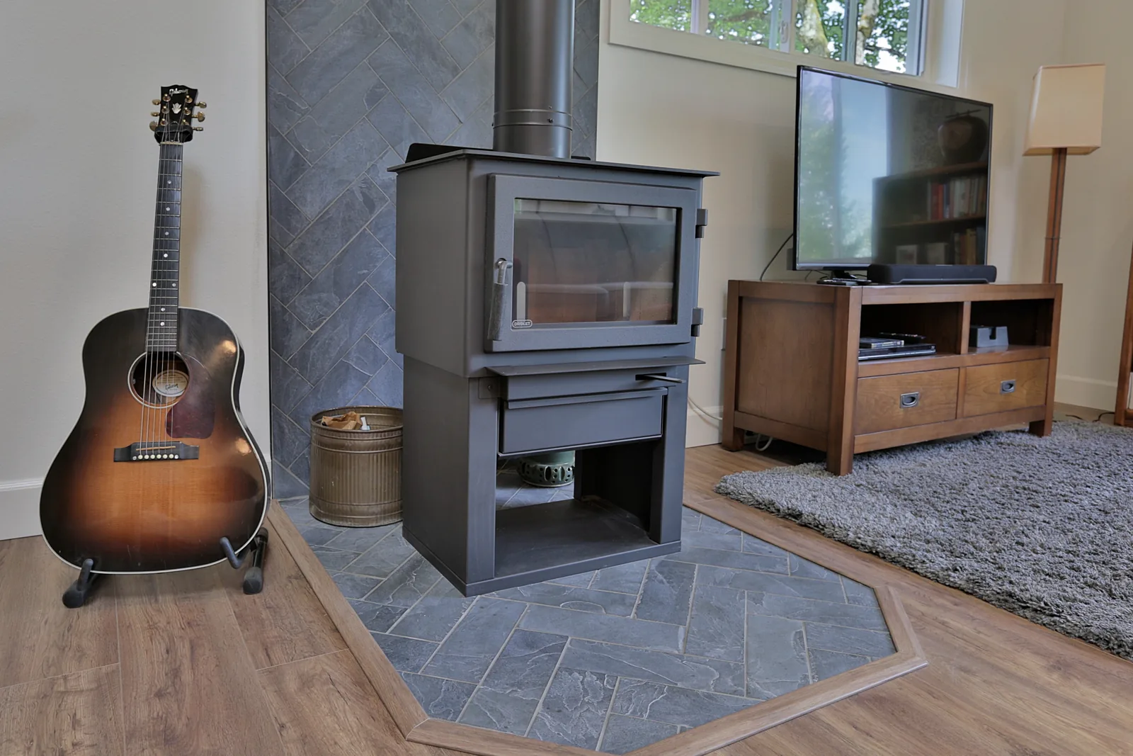Wood stove set on a slate herringbone hearth inlaid into the plank flooring