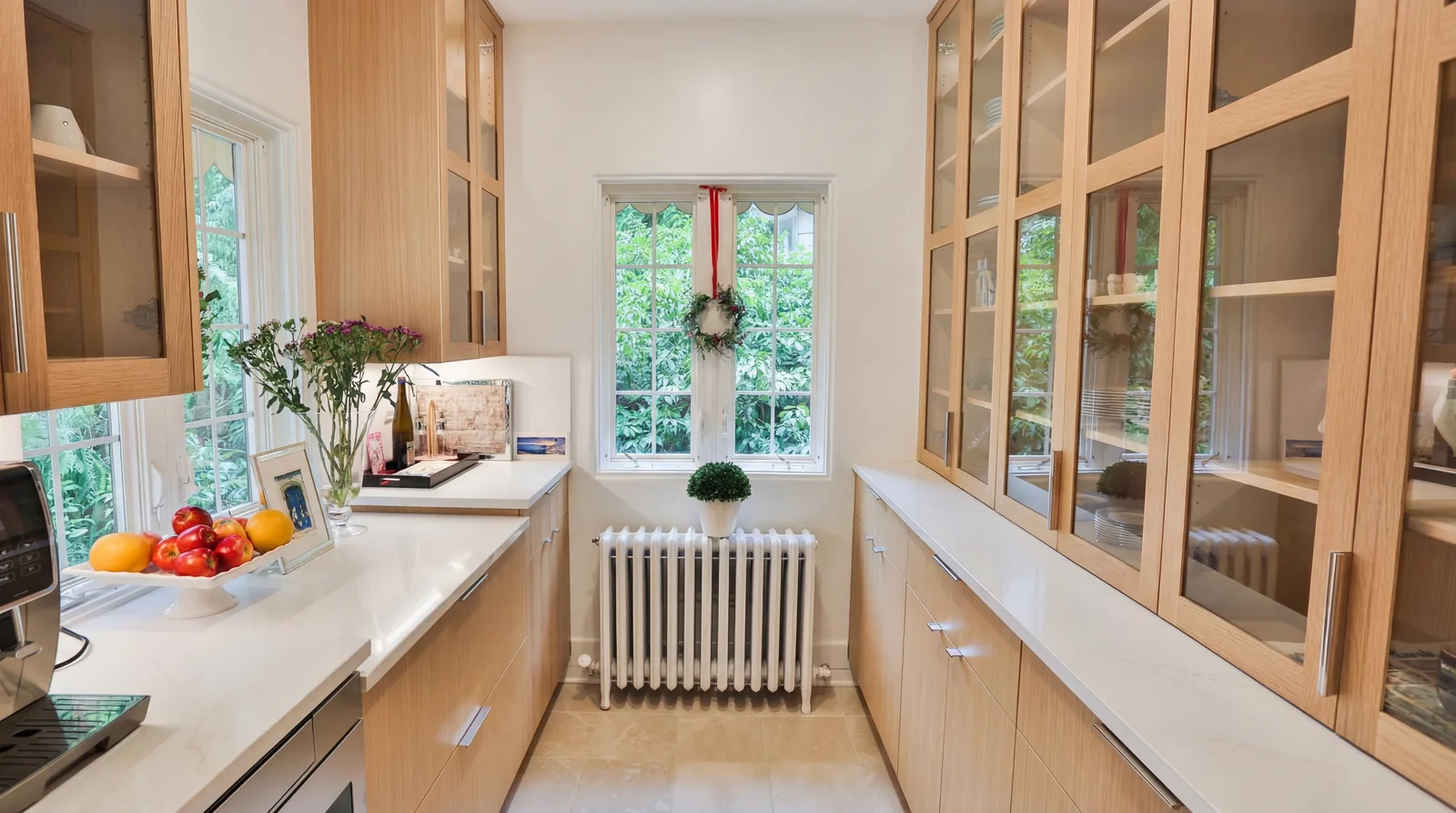 Butler's pantry with glass-front white oak cabinets and the home's original cast-iron radiator retained