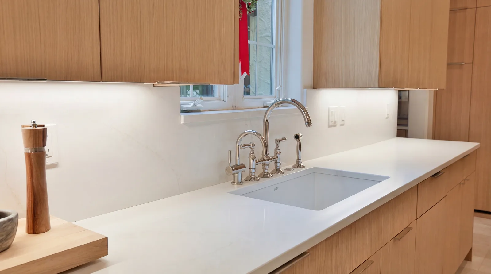 Kitchen sink run with polished nickel fittings and full-height stone backsplash