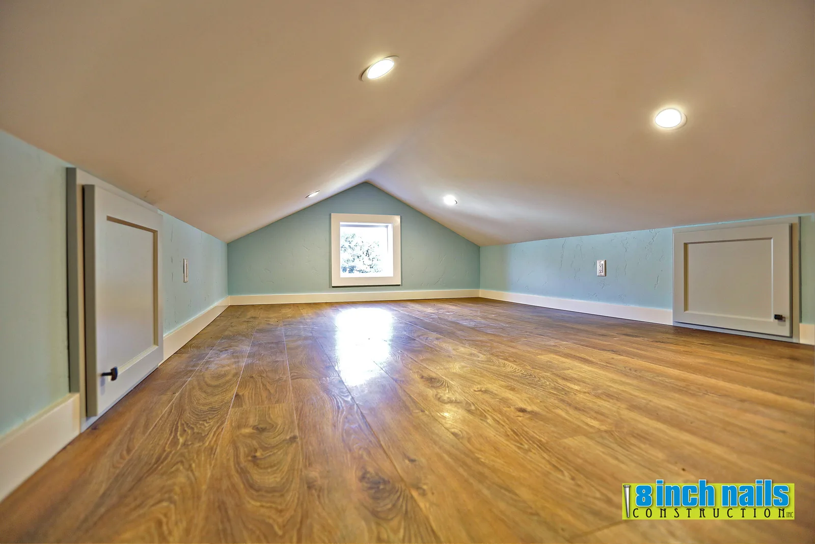 Sleeping loft under the gable with a window and recessed lighting