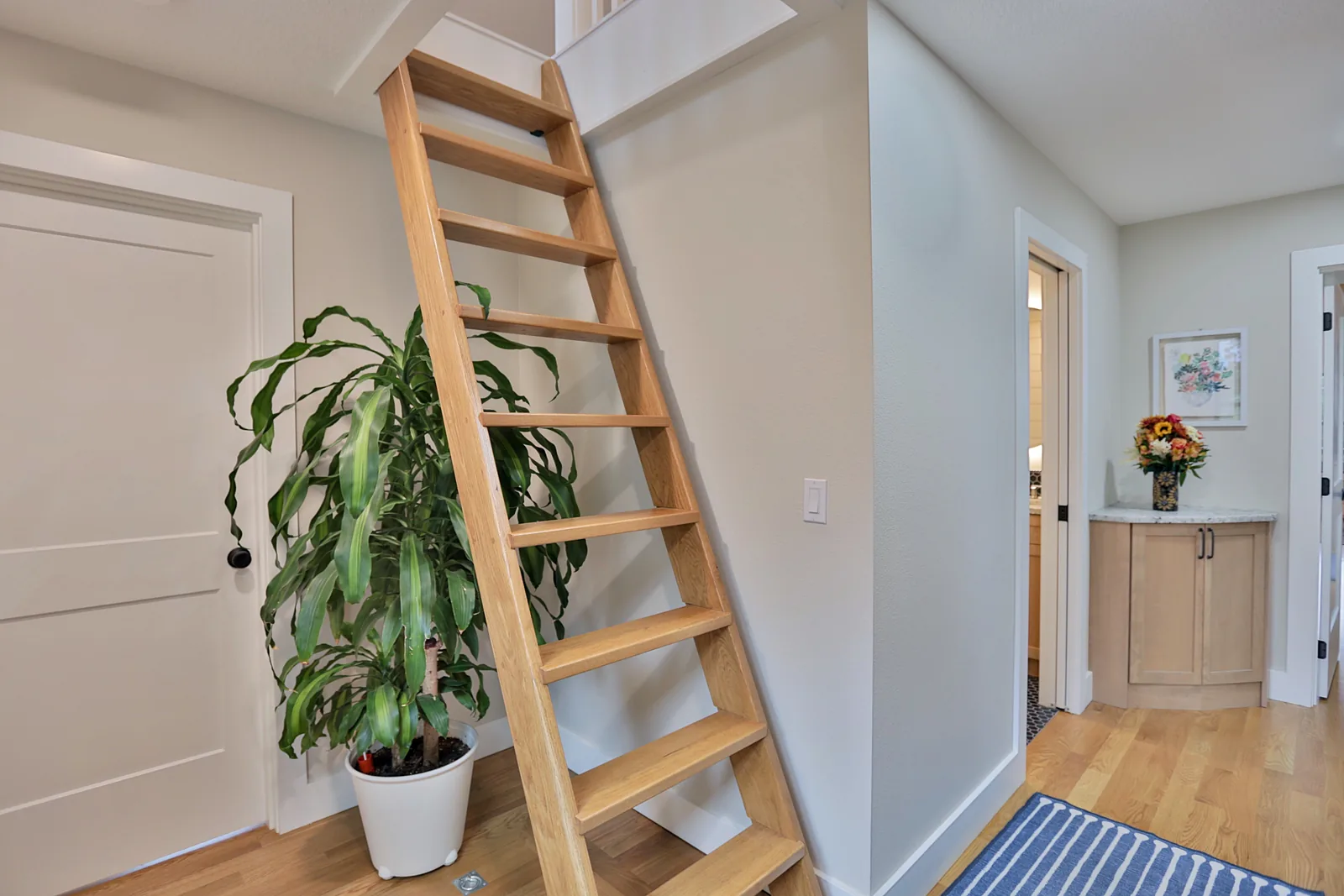 Hallway with white oak floors and the ladder to the loft storage
