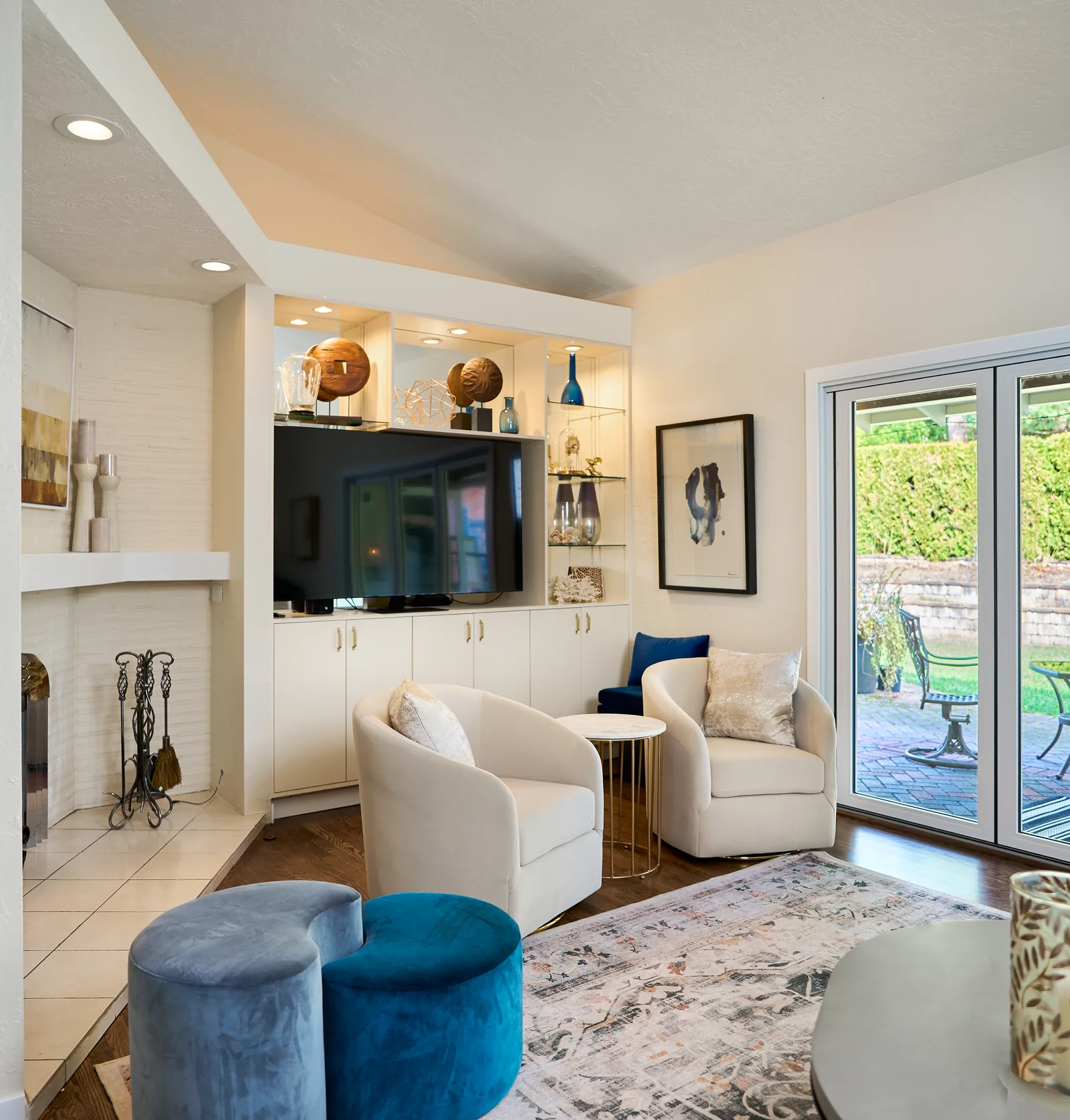 Built-in media wall with lit glass shelving beside a painted brick fireplace
