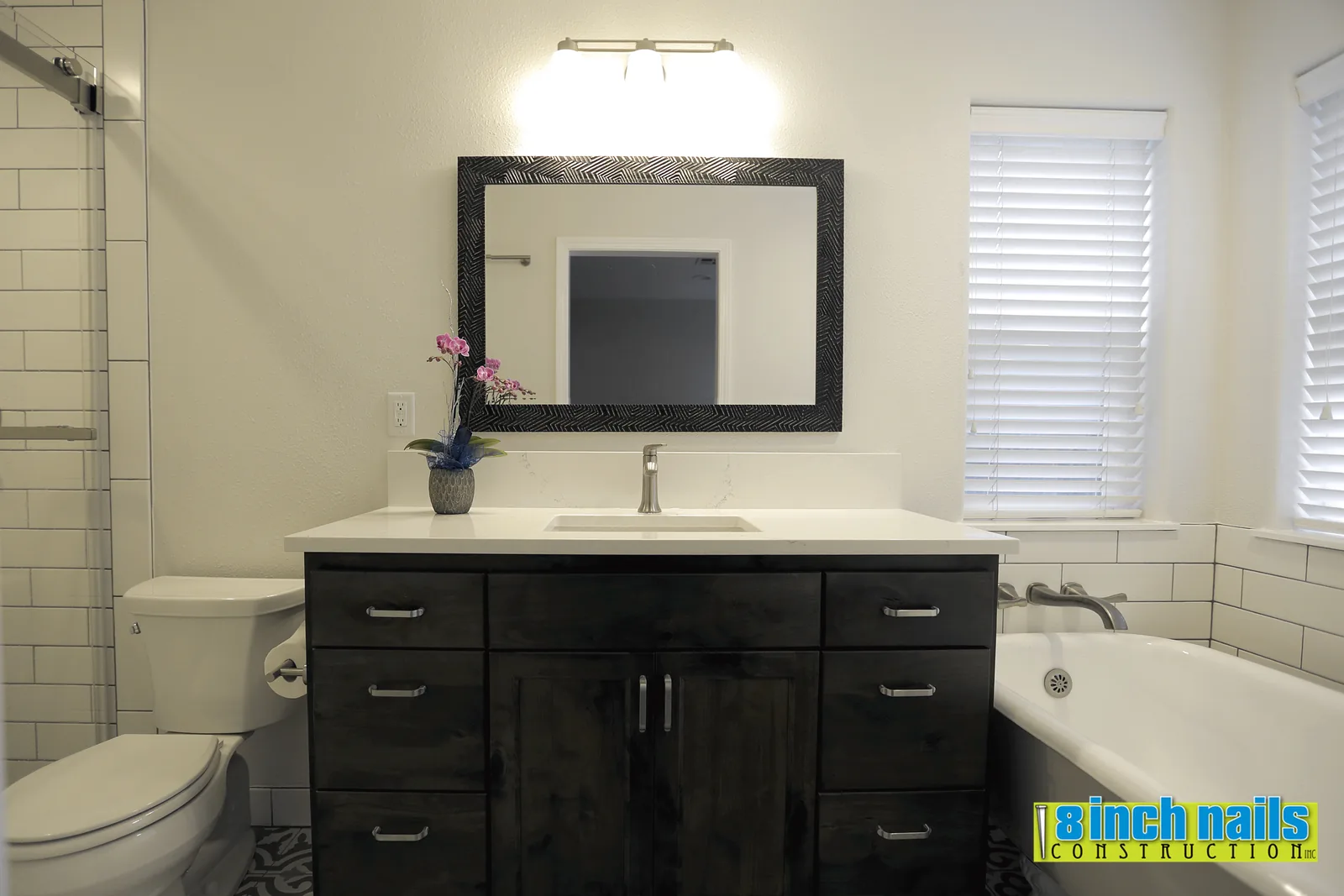 Dark-stained vanity with quartz counter, undermount sink and a textured black mirror